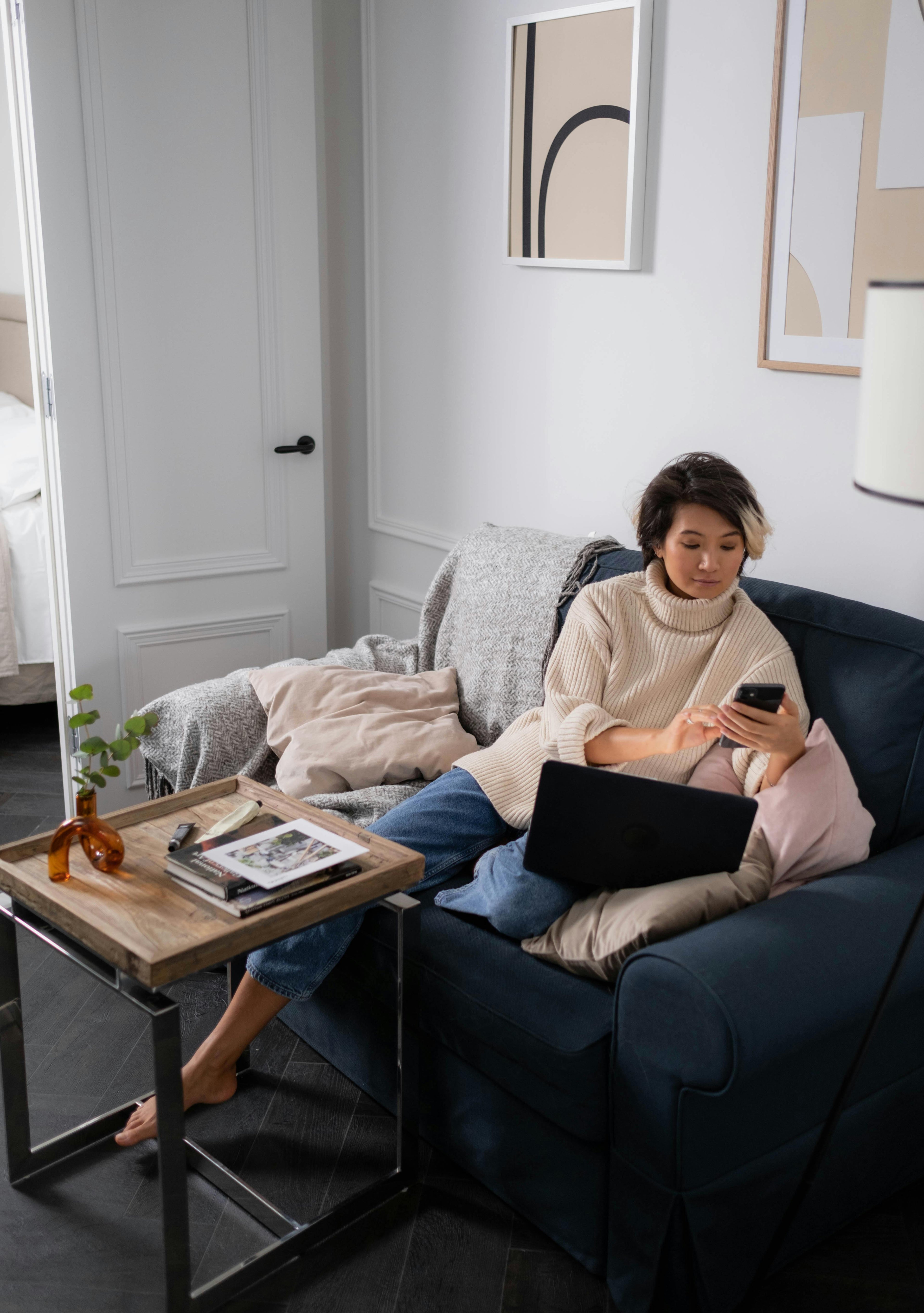 Cozy modern living room featuring a girl using her mobile while seated on a two-seater sofa with a stylish coffee table — premium furniture by The Meem Store.